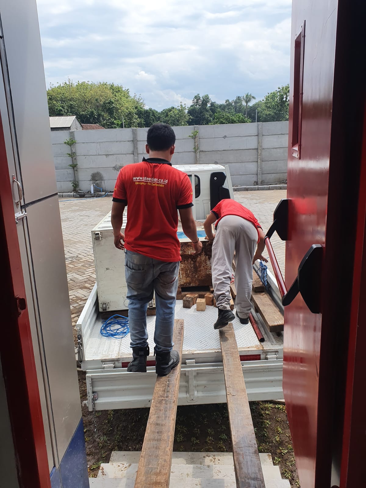 Brankas diturunkan dari bak kendaraan oleh teknisi